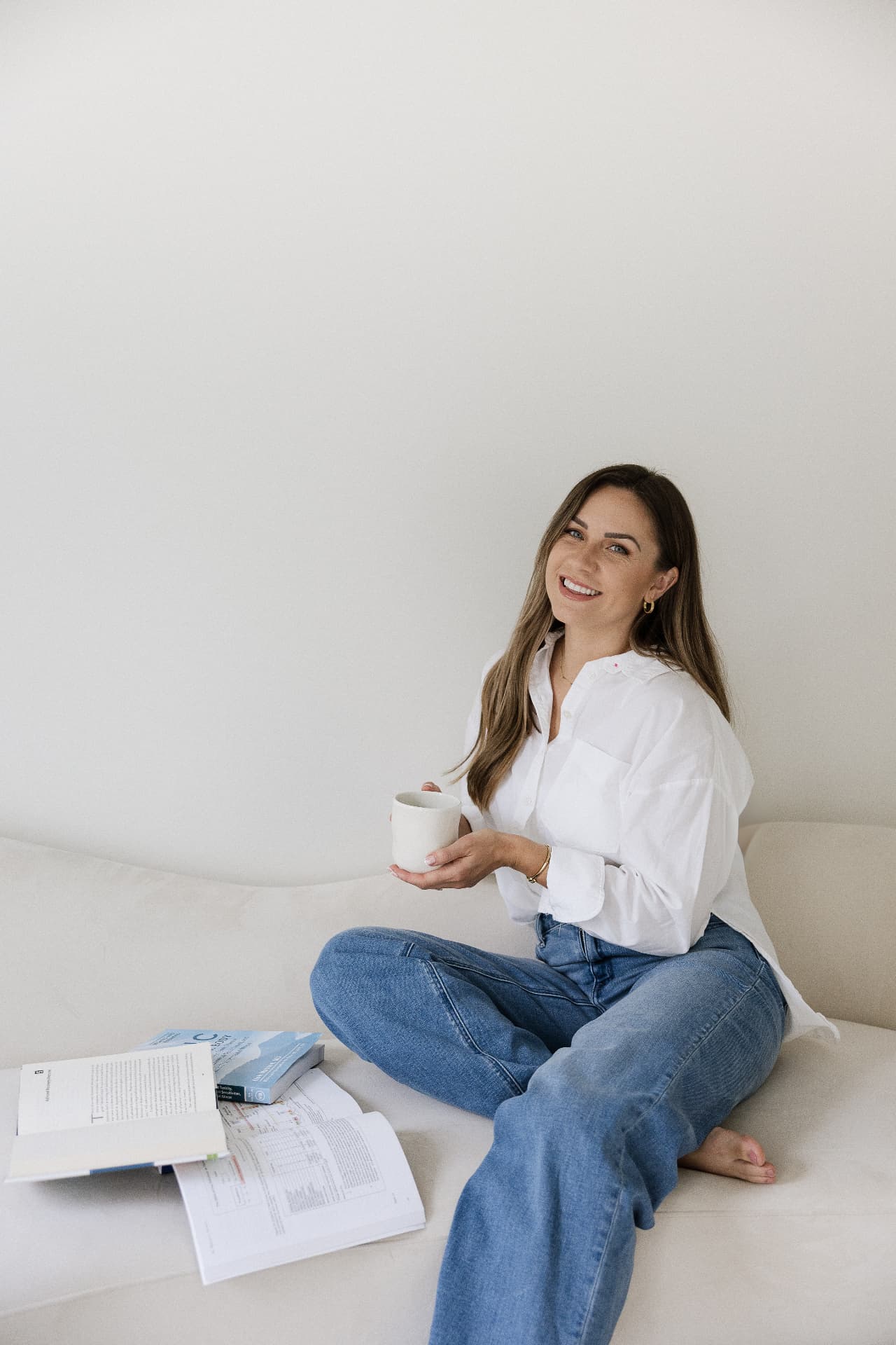 Alyssa seated with a warm mug beside open functional medicine textbooks